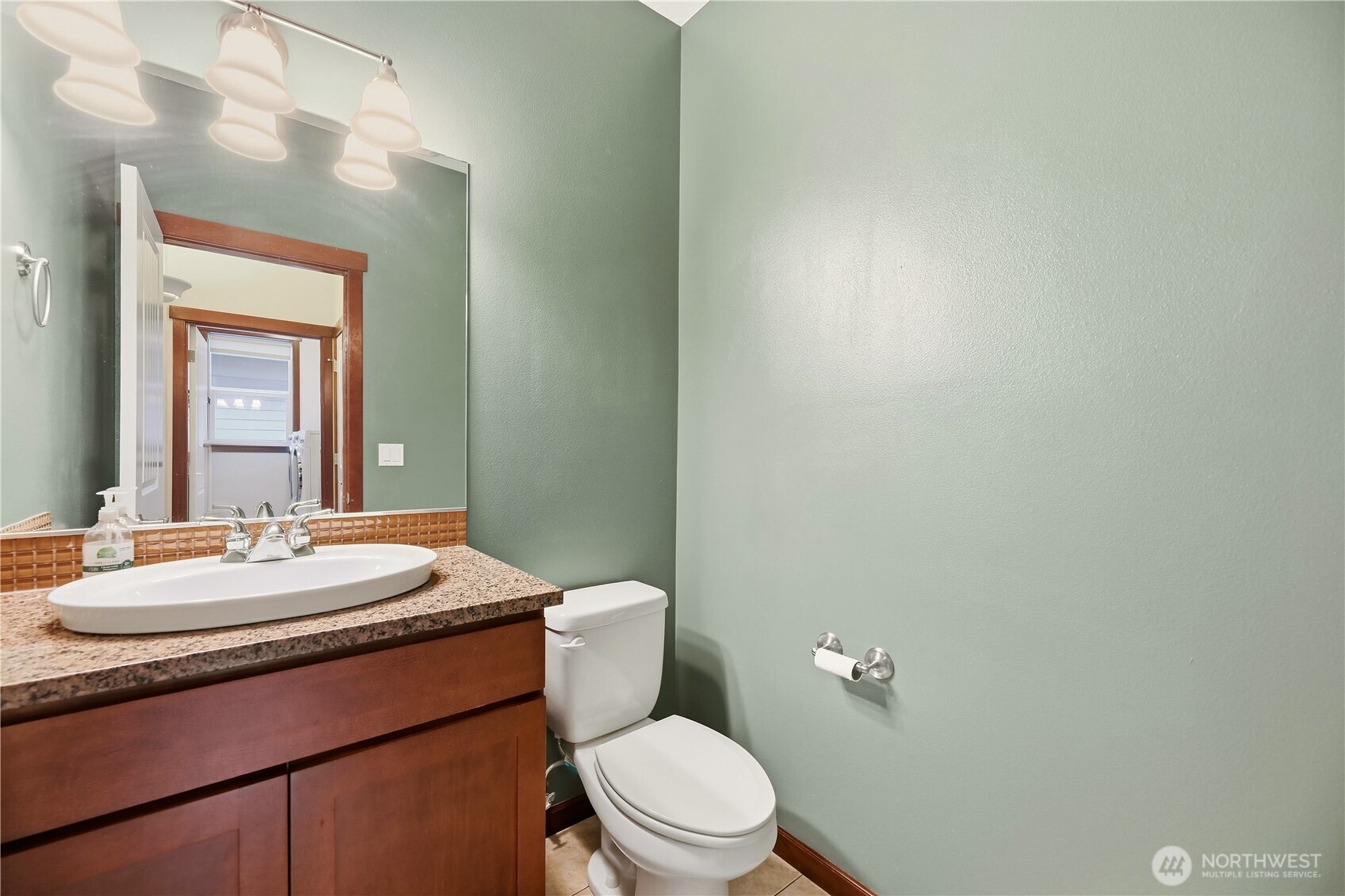Bathroom with a dark wood vanity, speckled countertop, oval sink, and white toilet.