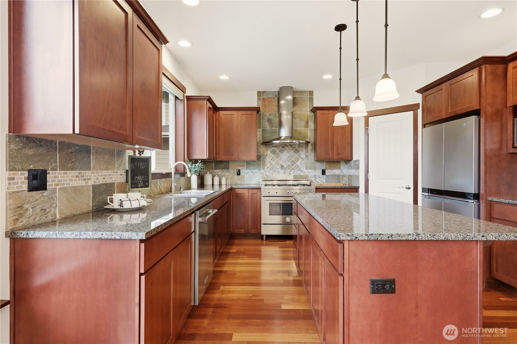 Kitchen with reddish-brown cabinetry, granite counters, stone backsplash, and a large island.