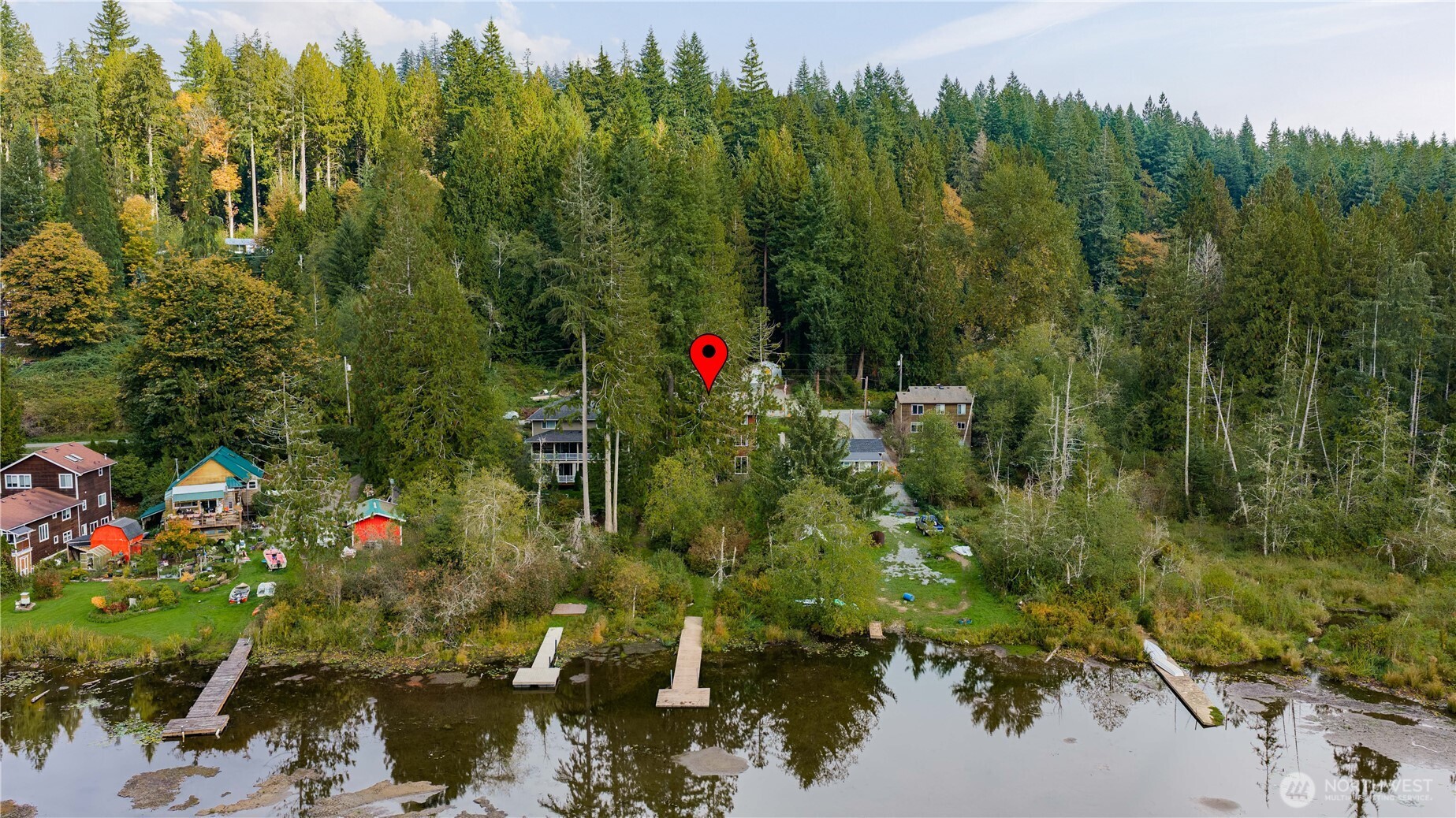 Aerial view of a wooded lakeside home with several docks along the shore.
