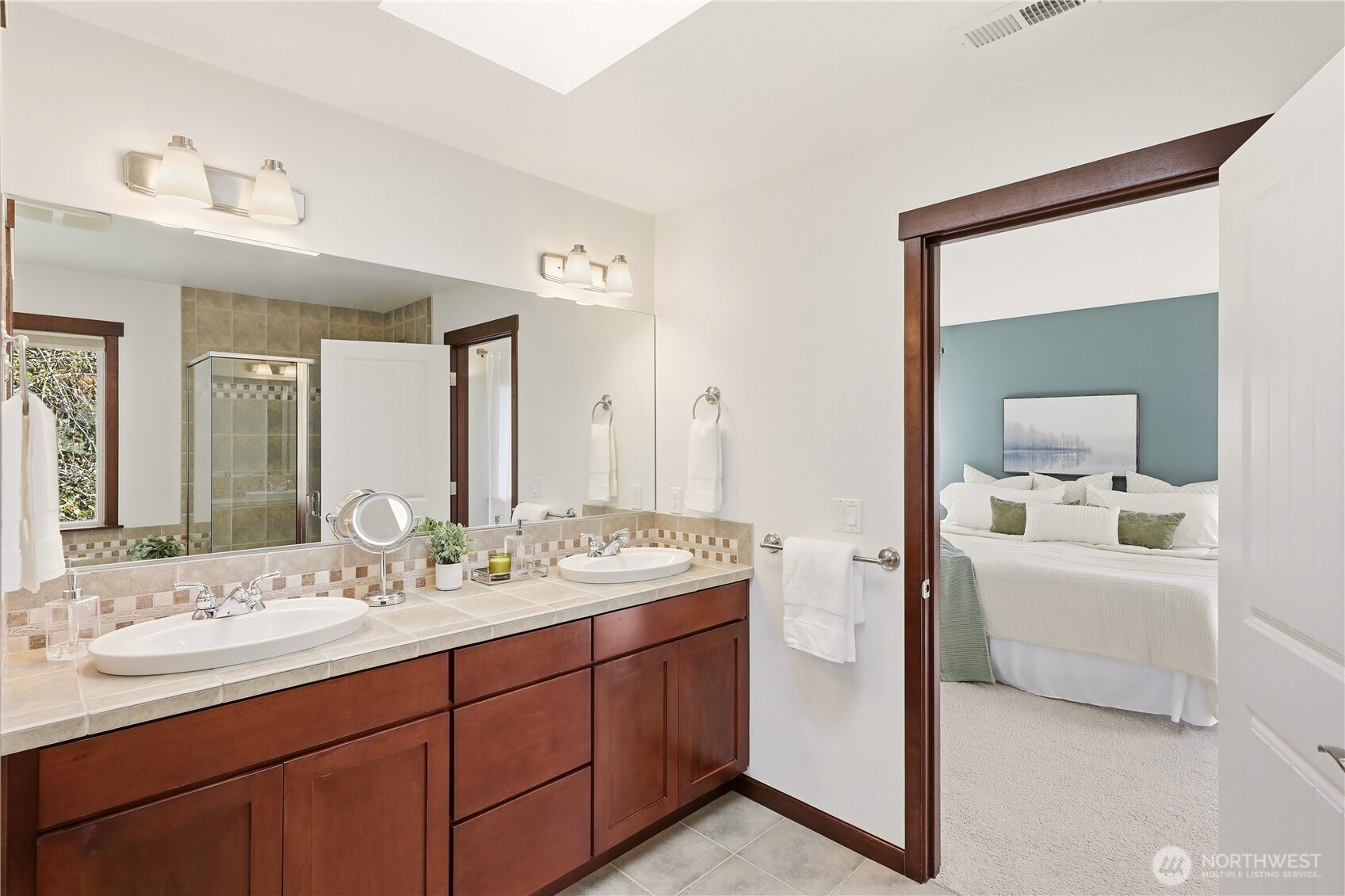 Primary bathroom with a tiled double vanity and an adjoining bedroom with a teal accent wall.