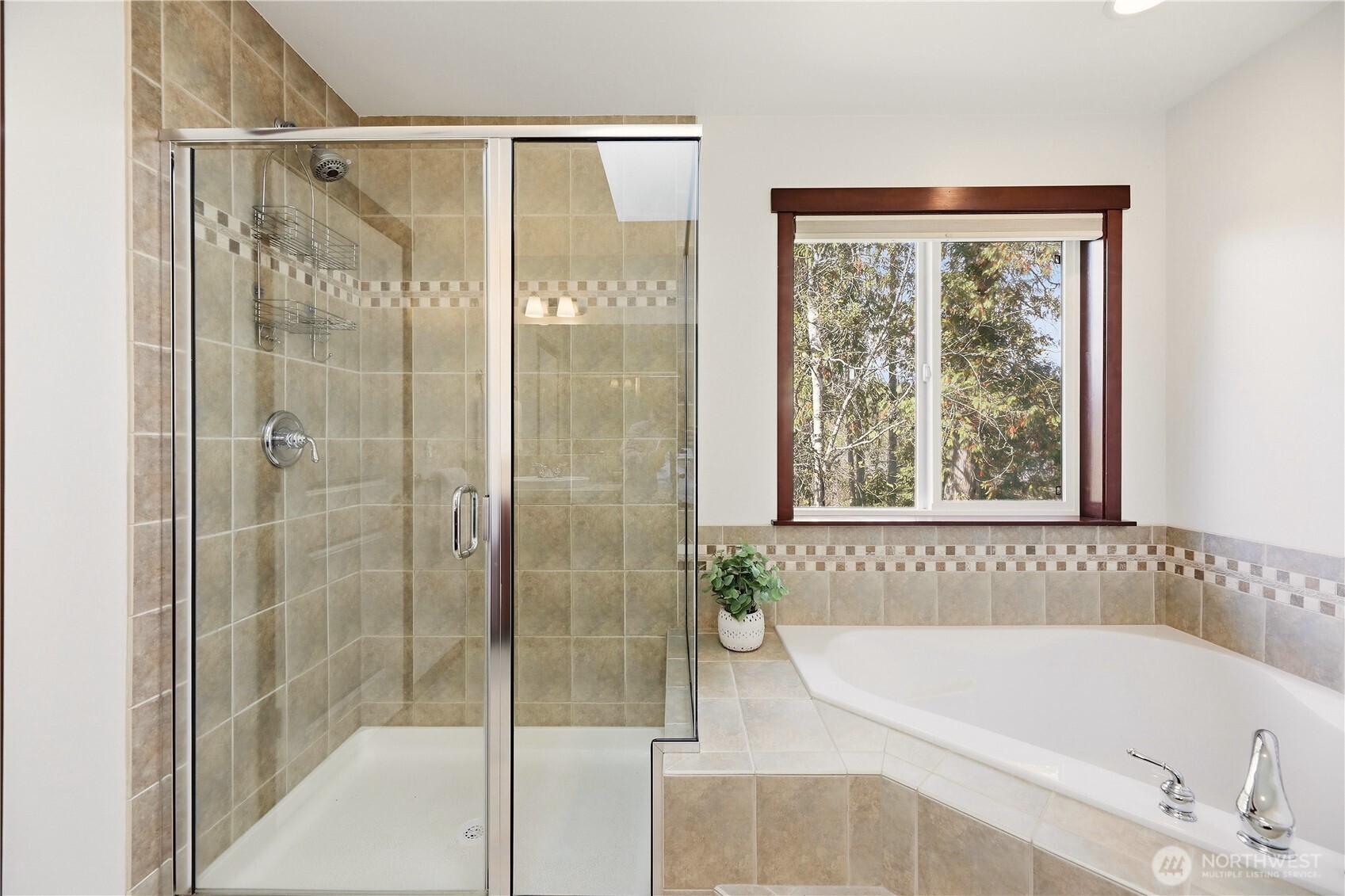 Bathroom with a tiled walk-in shower and corner soaking tub beneath a window.