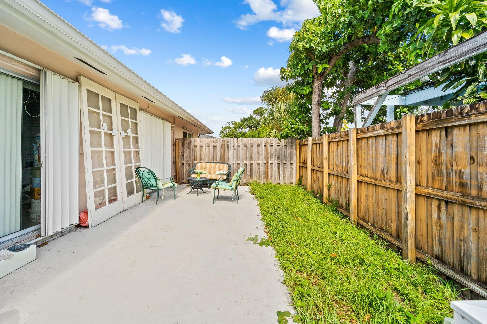 Backyard patio with outdoor seating, a wooden privacy fence, and a leafy tree.