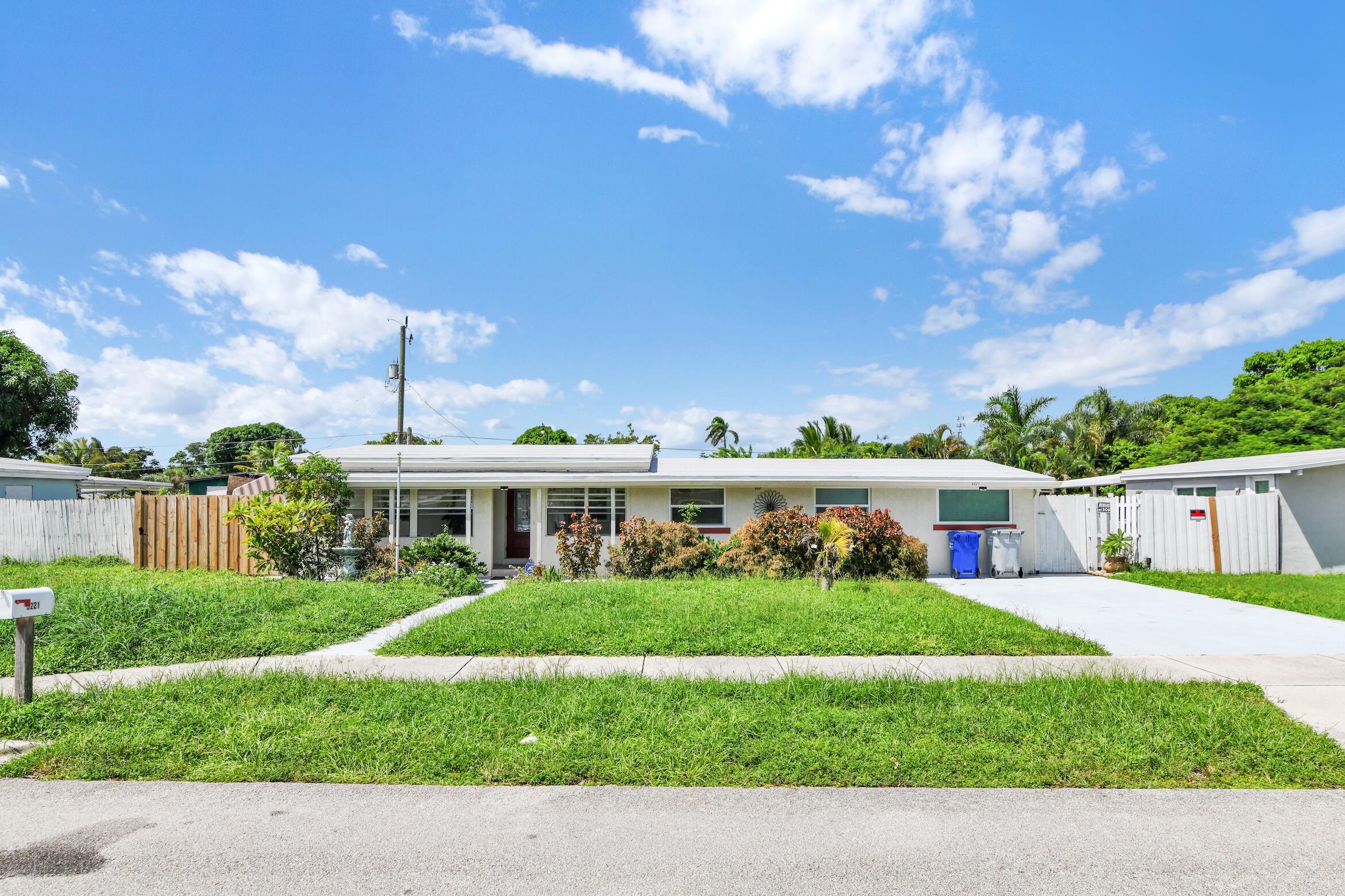 Single-story home with a broad lawn, landscaped front garden, and concrete driveway.