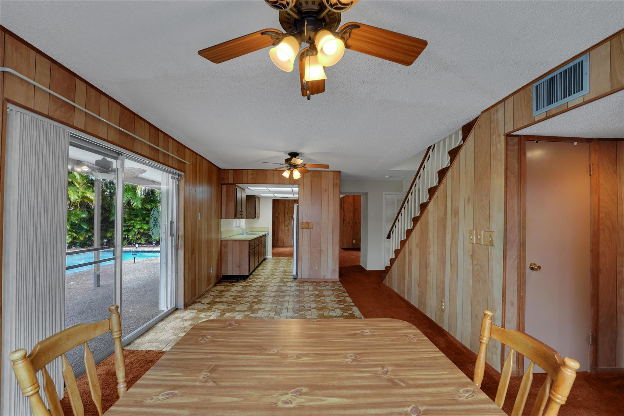 Dining area with wood paneling, a sliding glass door, and a view of the backyard pool.