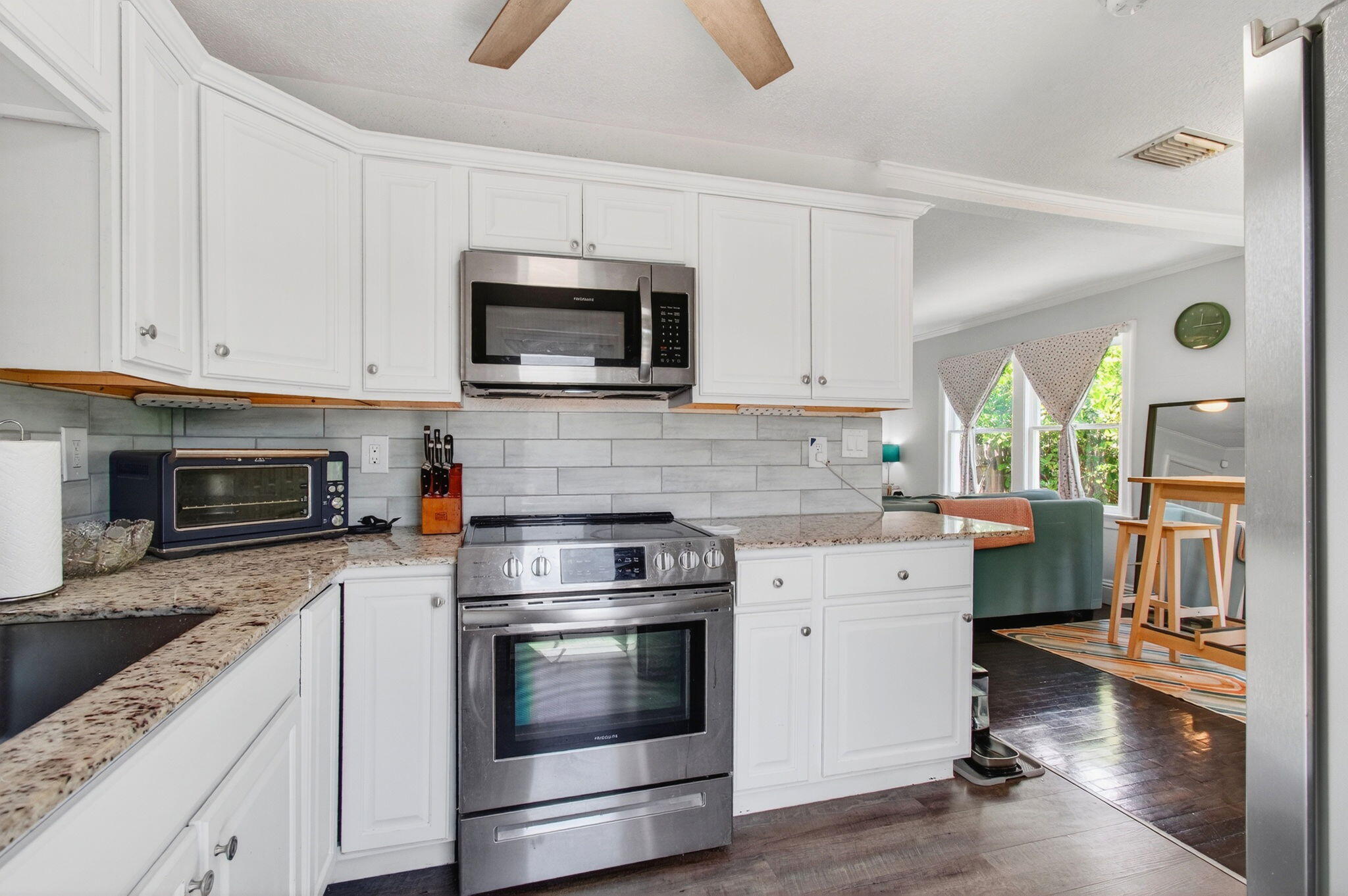 Kitchen with white cabinets, granite counters, stainless steel appliances, and an opening to the living area.