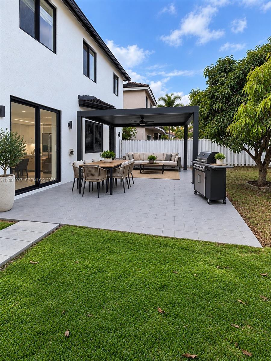 Backyard patio with a black pergola, dining set, lounge seating, and grill beside a green lawn.