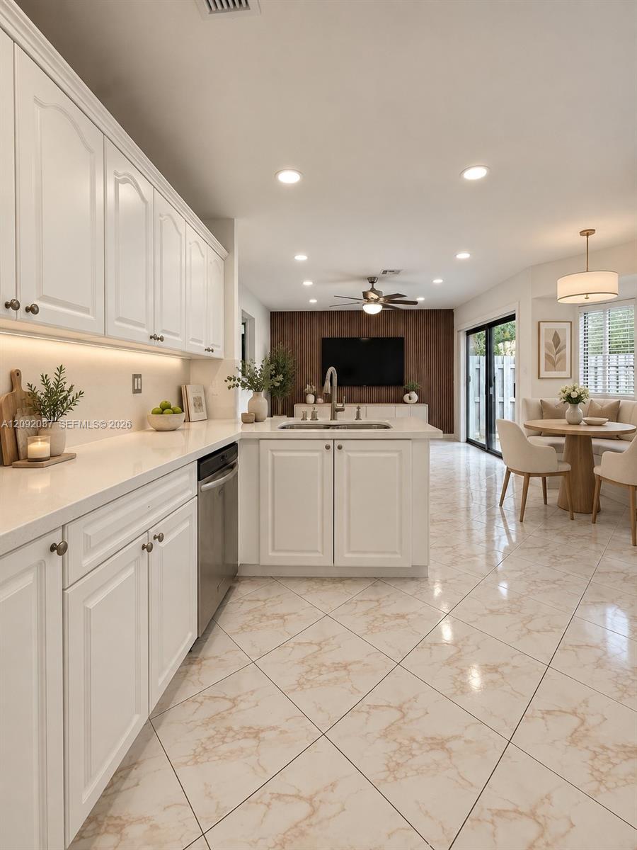 Kitchen with white cabinets, a sink island, marble-pattern tile floors, and a wood-slat accent wall.