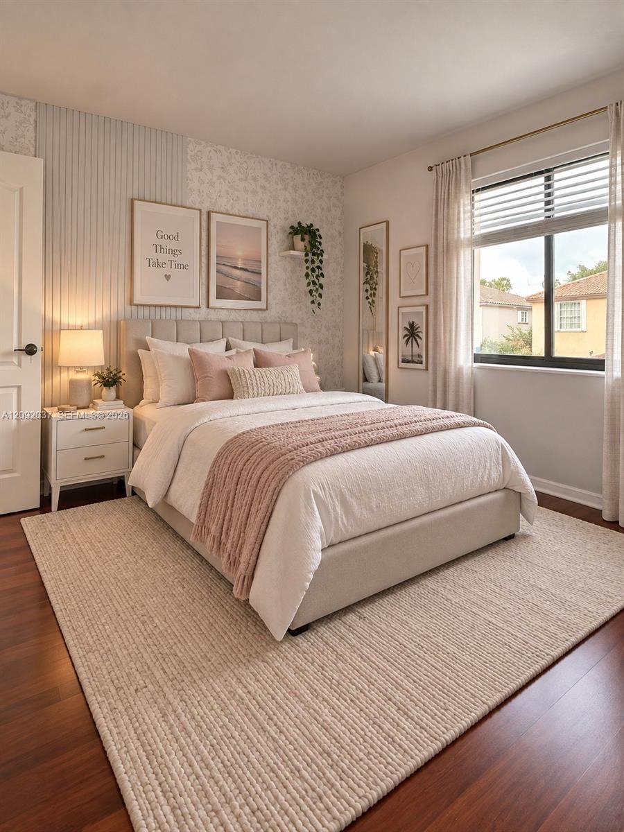 Staged bedroom with blush bedding, a woven rug, patterned accent wall, and a bright window.