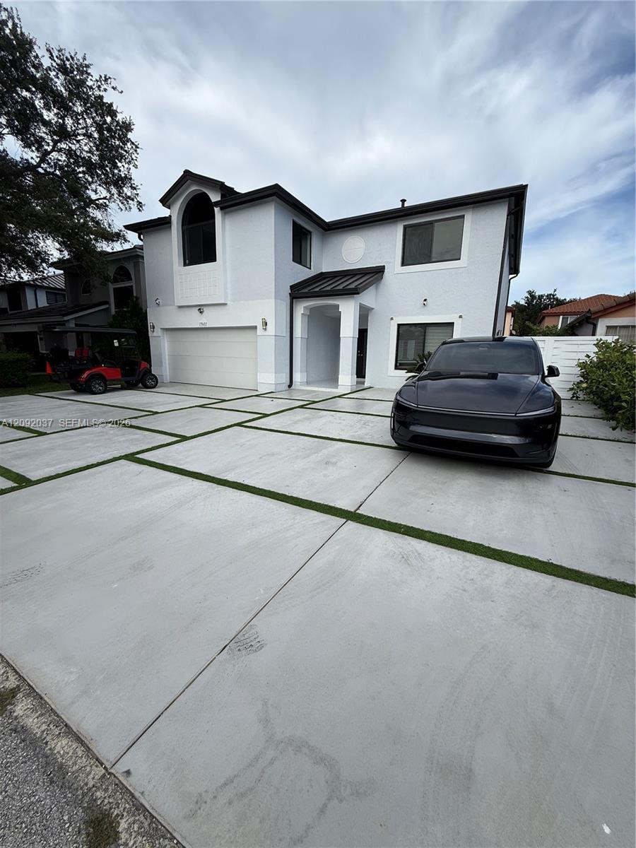 Modern two-story white house with black trim, garage, and a wide driveway; a dark car is parked out front.