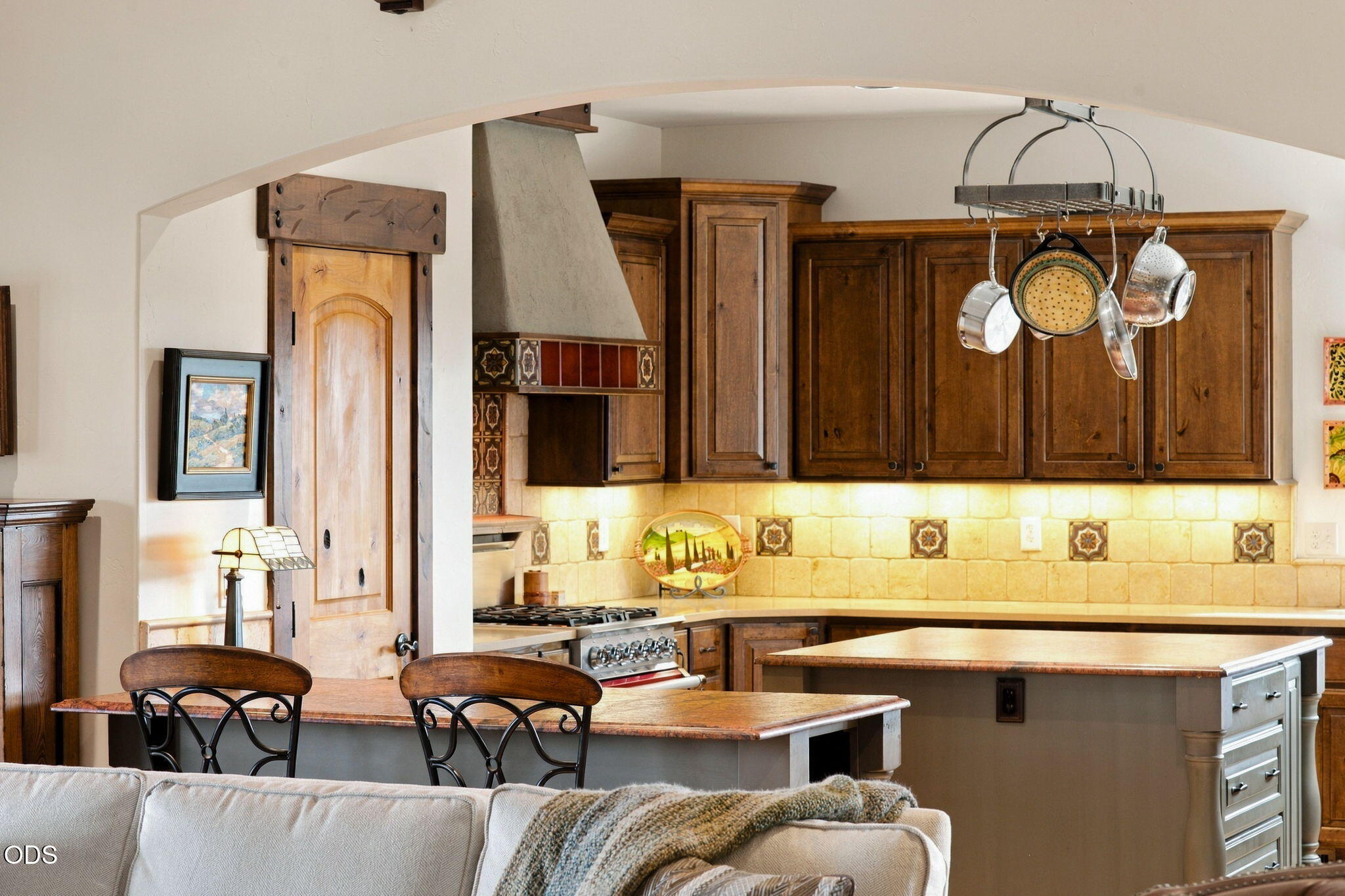Rustic kitchen with dark wood cabinets, decorative tile backsplash, gas range, and a large island.