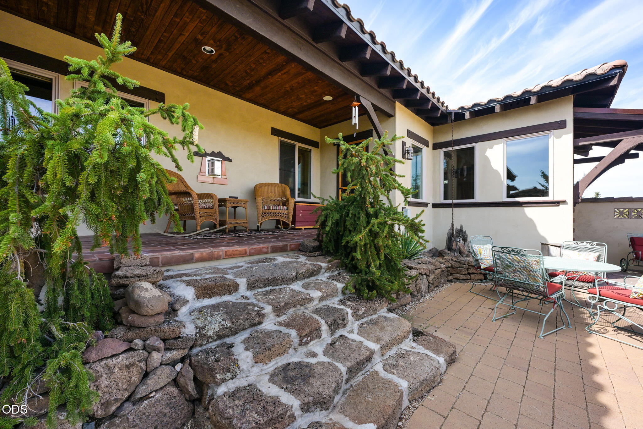 Furnished home patio with broad stone steps, covered wicker seating, and an outdoor dining area.