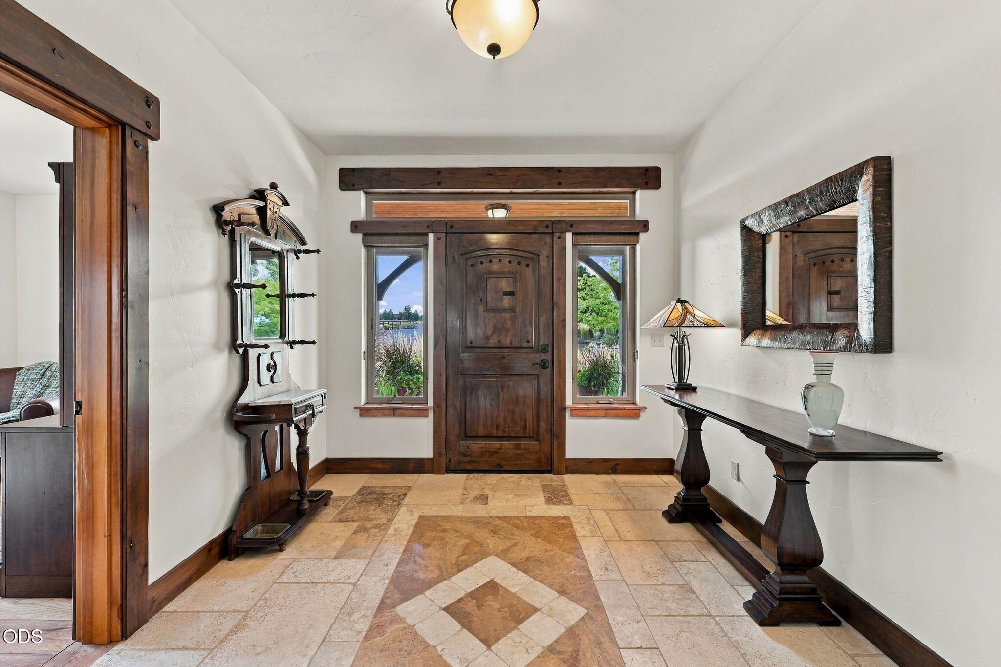 Furnished entry foyer with a dark wood front door, sidelights, and geometric stone tile floor.