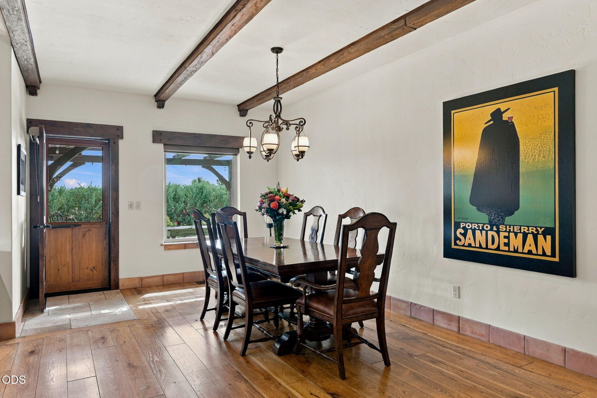 Dining room with dark wood furniture, exposed beams, and a large Sandeman poster.