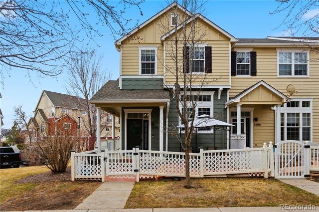 Two-story yellow house with green lower siding, a covered porch, and a white lattice fence.