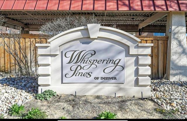 Whispering Pines of Denver entrance sign beneath a red metal canopy.