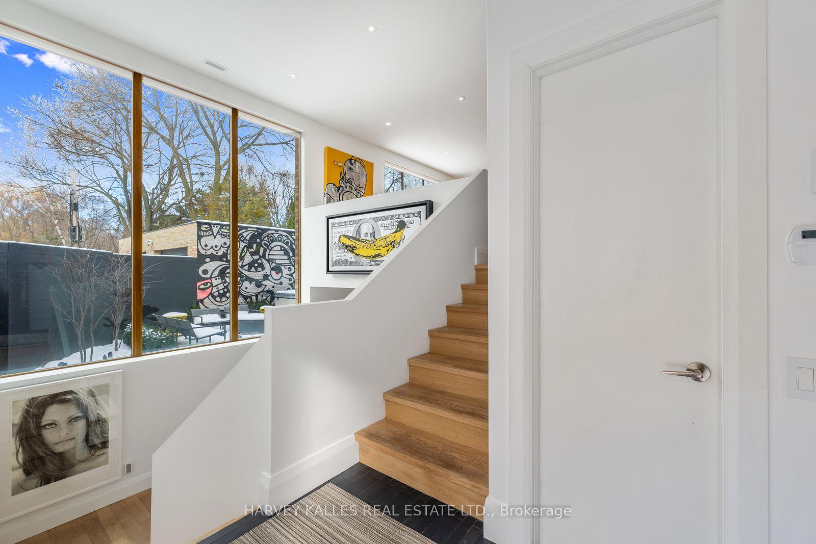 Modern stairwell with wide wood steps and tall windows overlooking a patio.