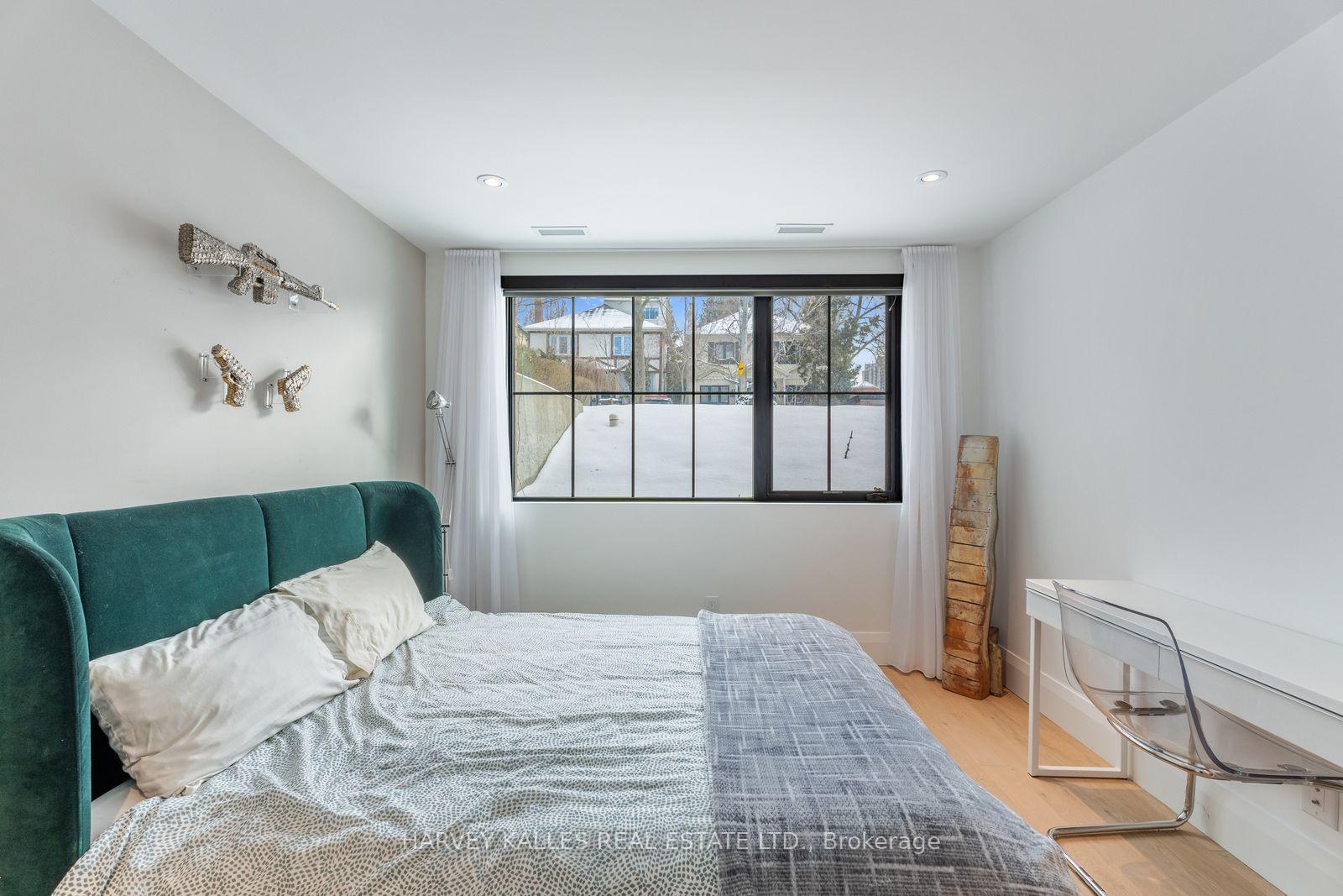 Bedroom with a teal upholstered bed and a large window overlooking a snow-covered yard.