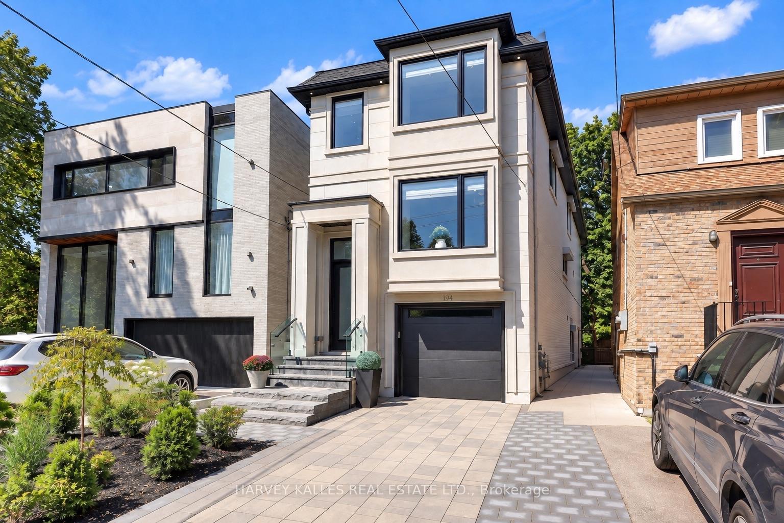 Modern two-story house with light exterior, dark-framed windows, attached garage, and paved driveway.