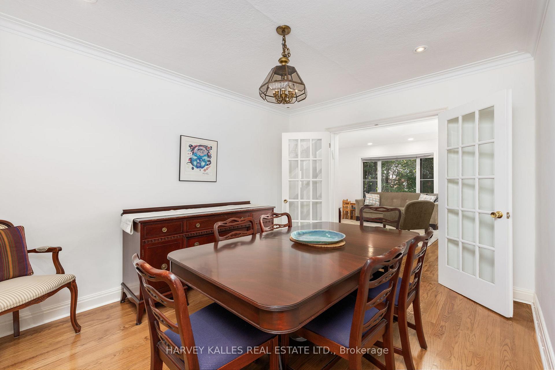 Furnished dining room with a dark wood table, hardwood floors, and open French doors to a sitting room.
