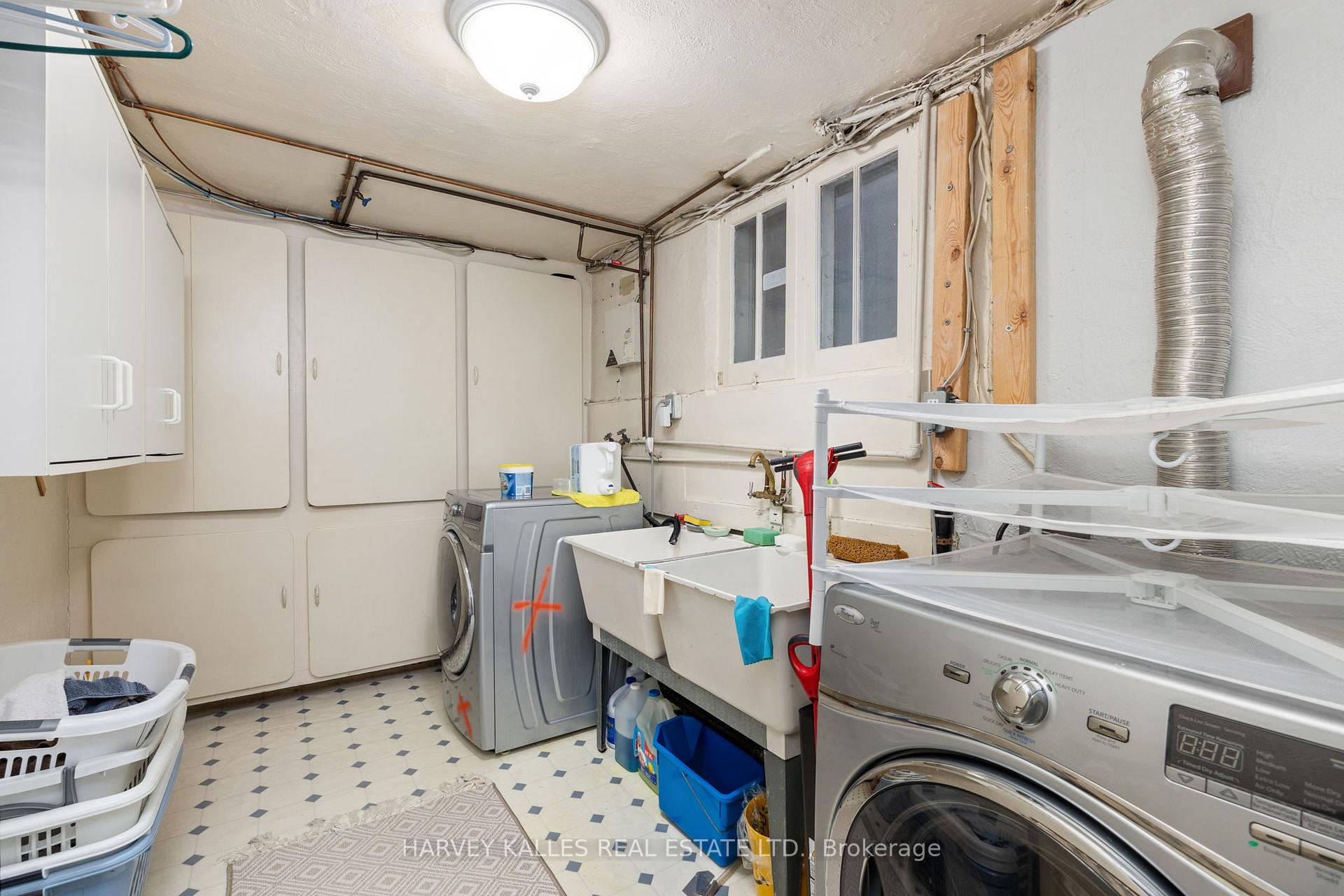 Laundry room with washer and dryer, double utility sink, and wall-mounted storage cabinets.
