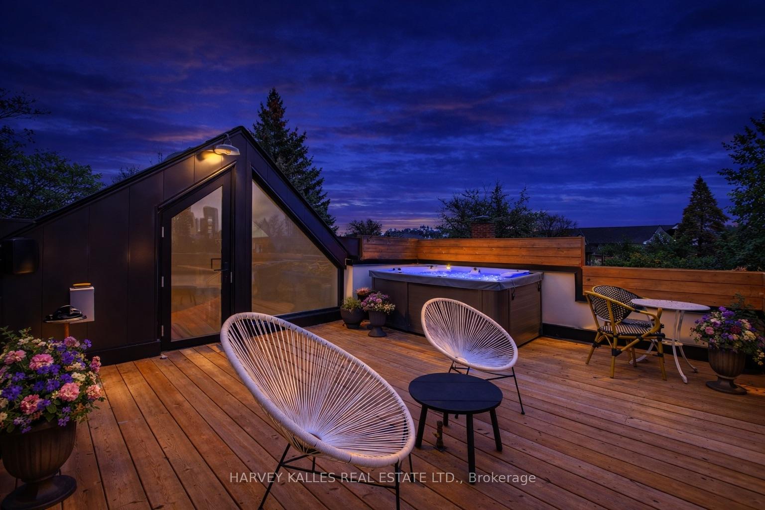 Rooftop deck with a hot tub, white lounge chairs and wood decking beneath a deep blue dusk sky.