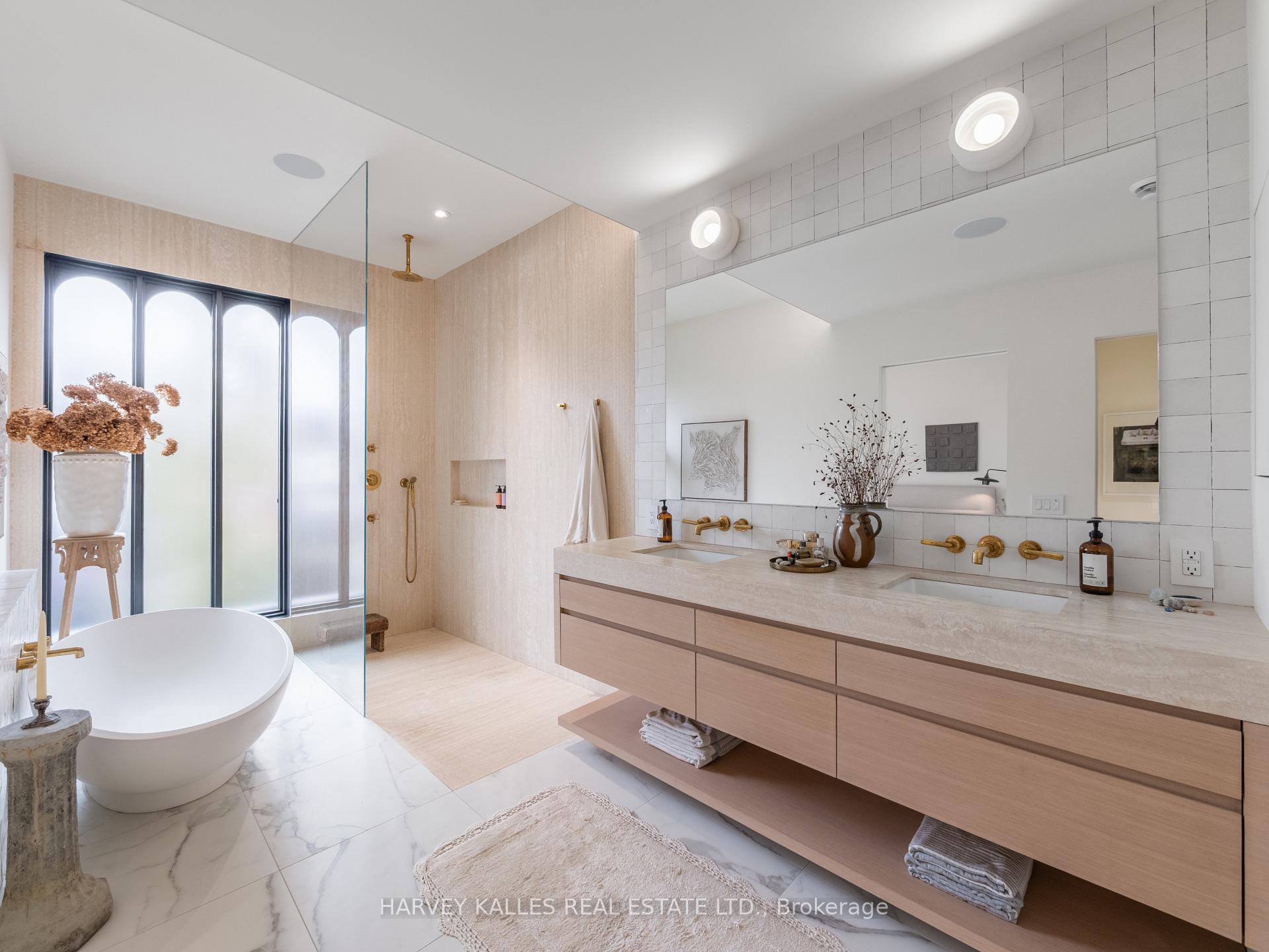 Modern bathroom with a freestanding tub, frosted windows, and a long double vanity with brass fixtures.