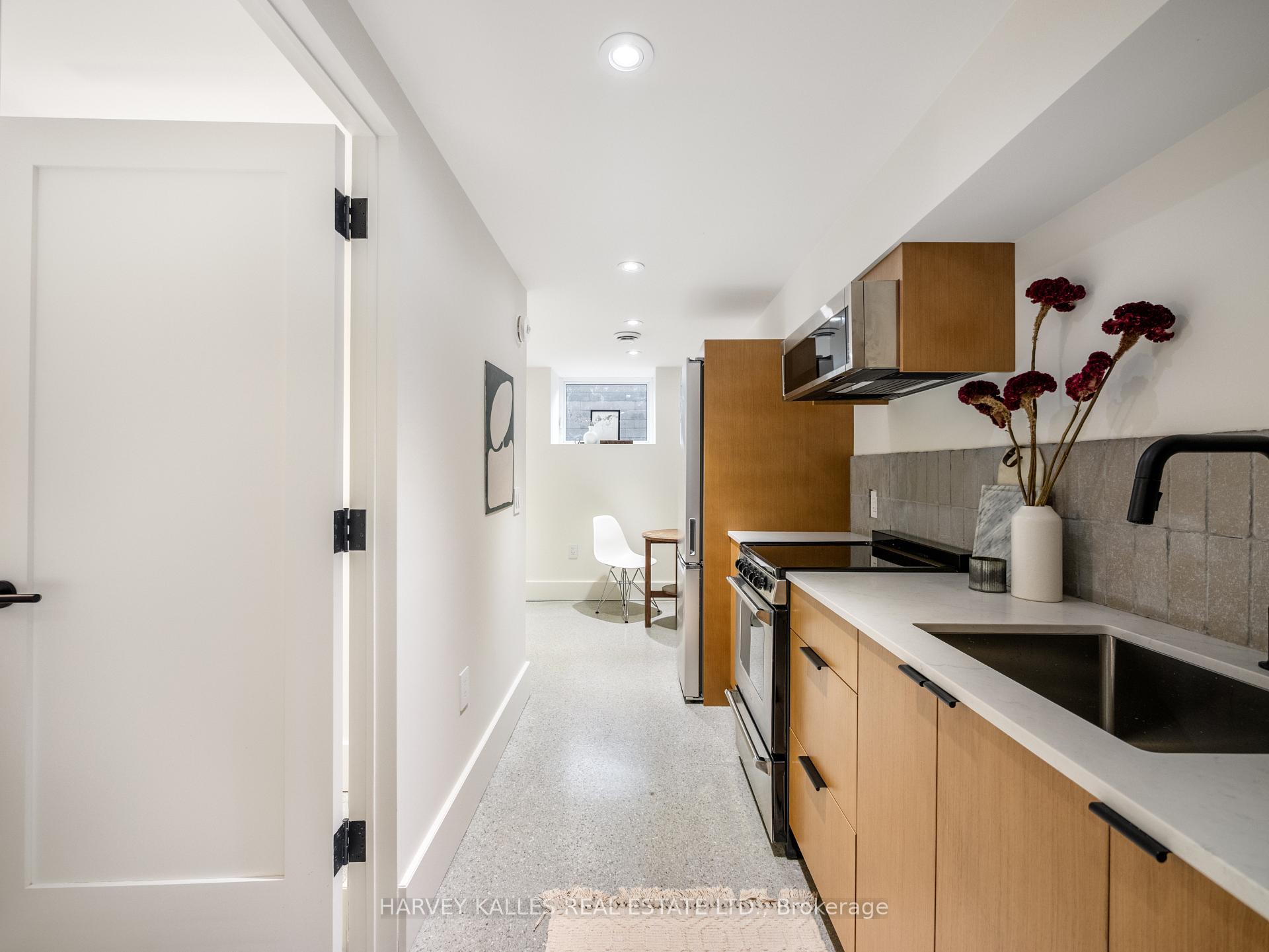 Modern galley kitchen with warm wood cabinets, gray tile backsplash, and a small dining nook.