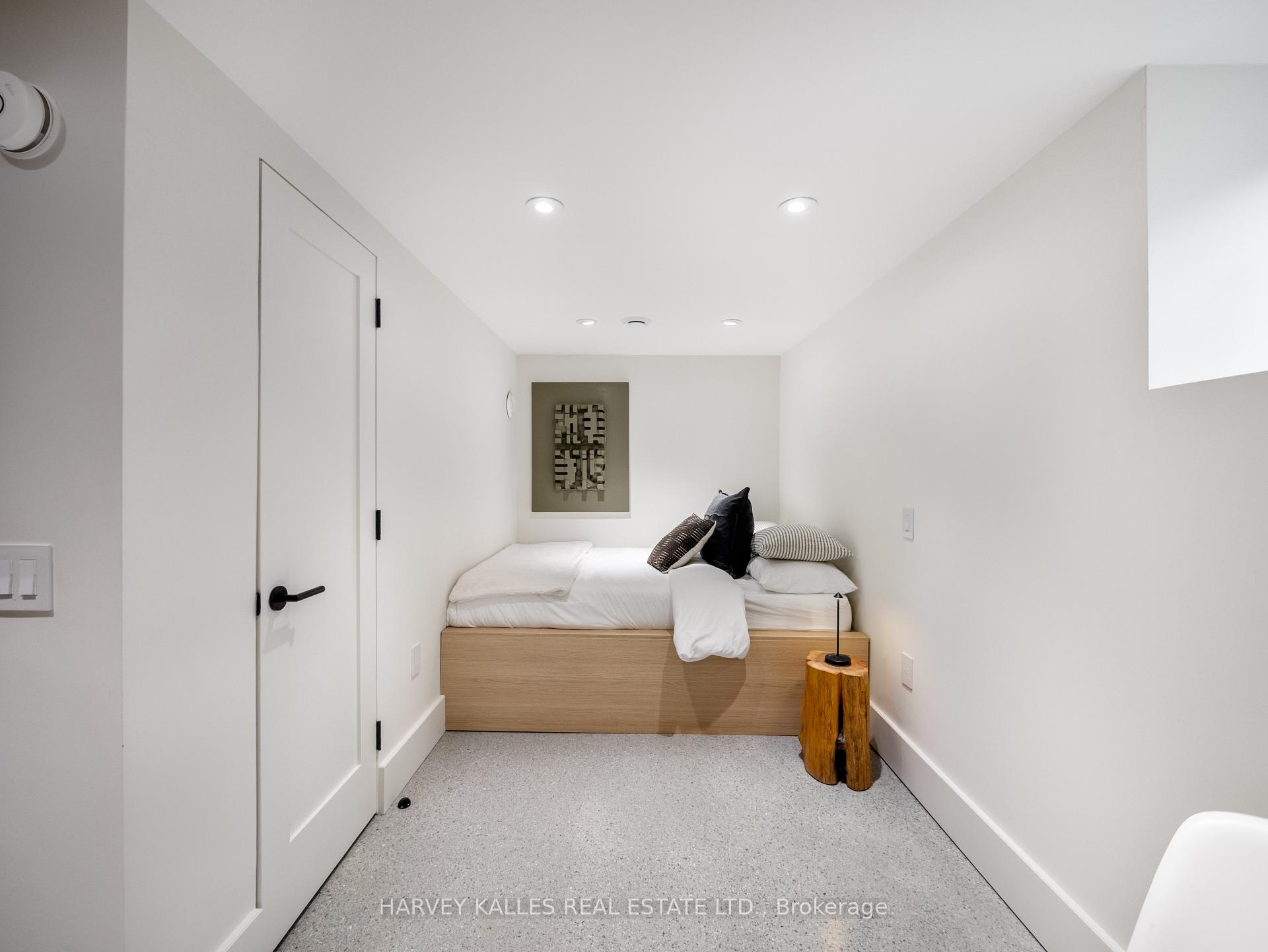 Compact bedroom with a low wood platform bed, white bedding, and a rustic stump side table.