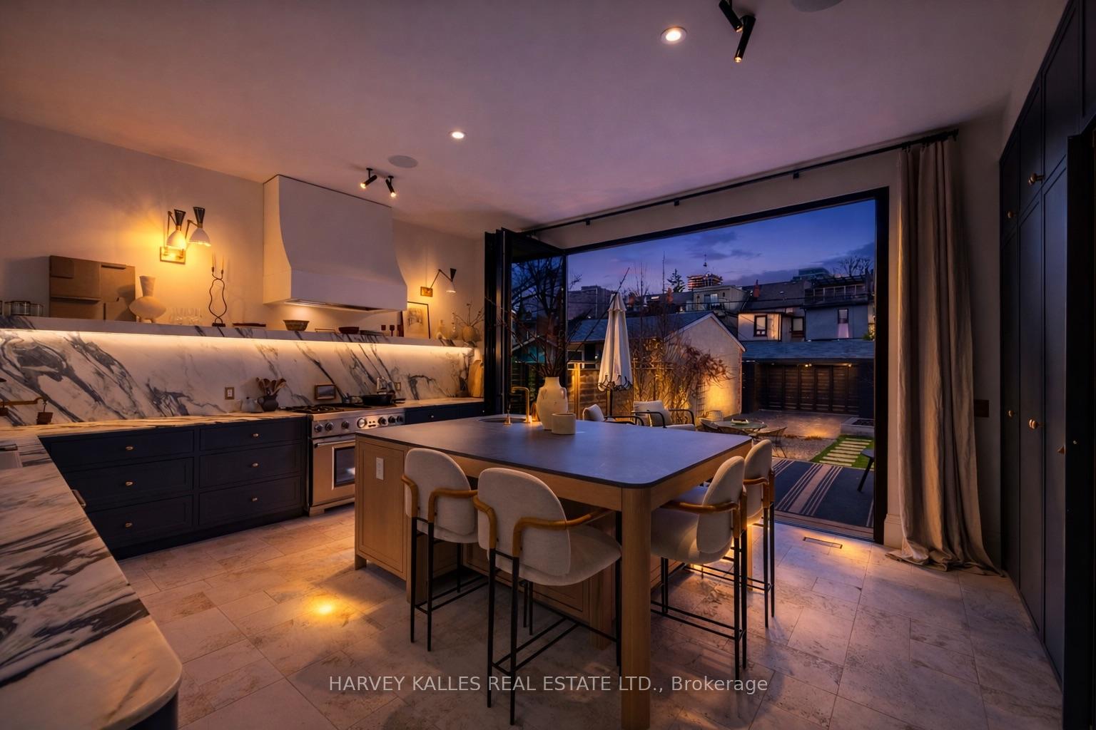 Modern kitchen with a veined marble backsplash, large island, and folding doors opening to a patio.