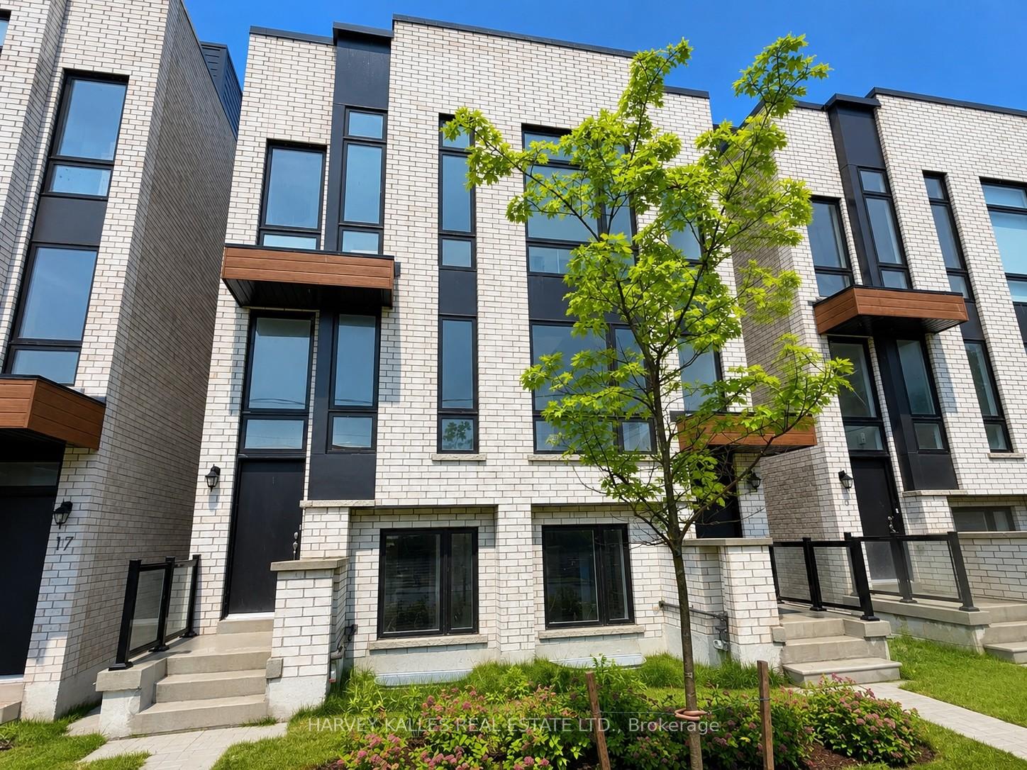 Modern white-brick townhomes with black-framed windows and wood-accented entry canopies.