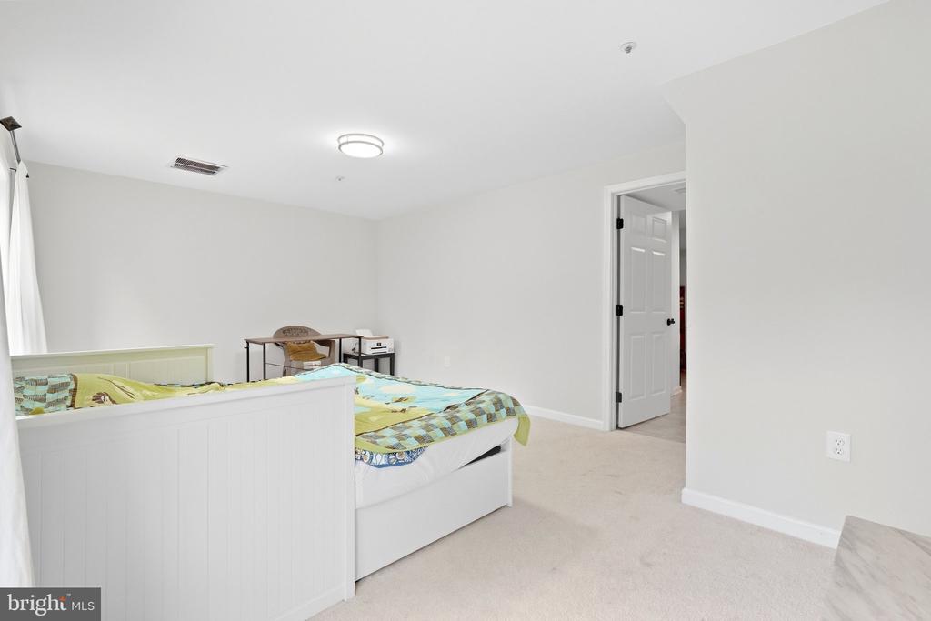 Bedroom with a white bed, colorful bedding, and an open doorway.
