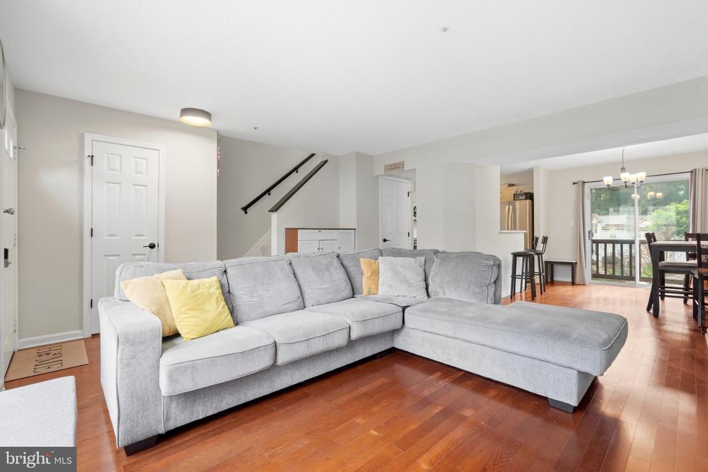 Living room with a gray sectional, yellow pillows, hardwood floors, and sliding doors to a balcony.
