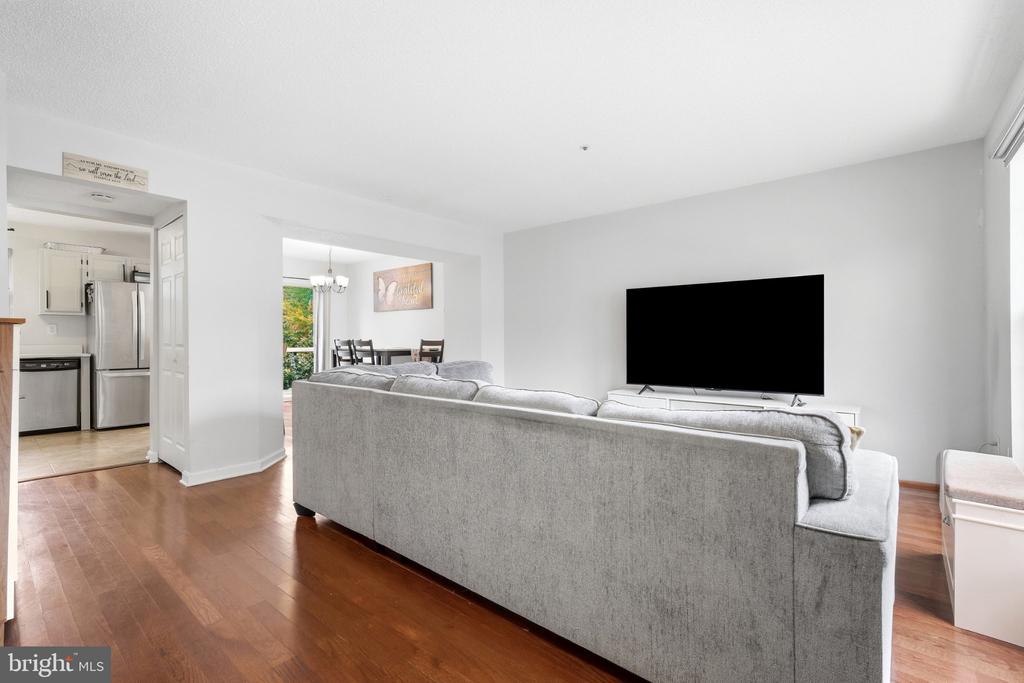 Living room with a gray sectional, hardwood floors, and an open view into the kitchen and dining area.