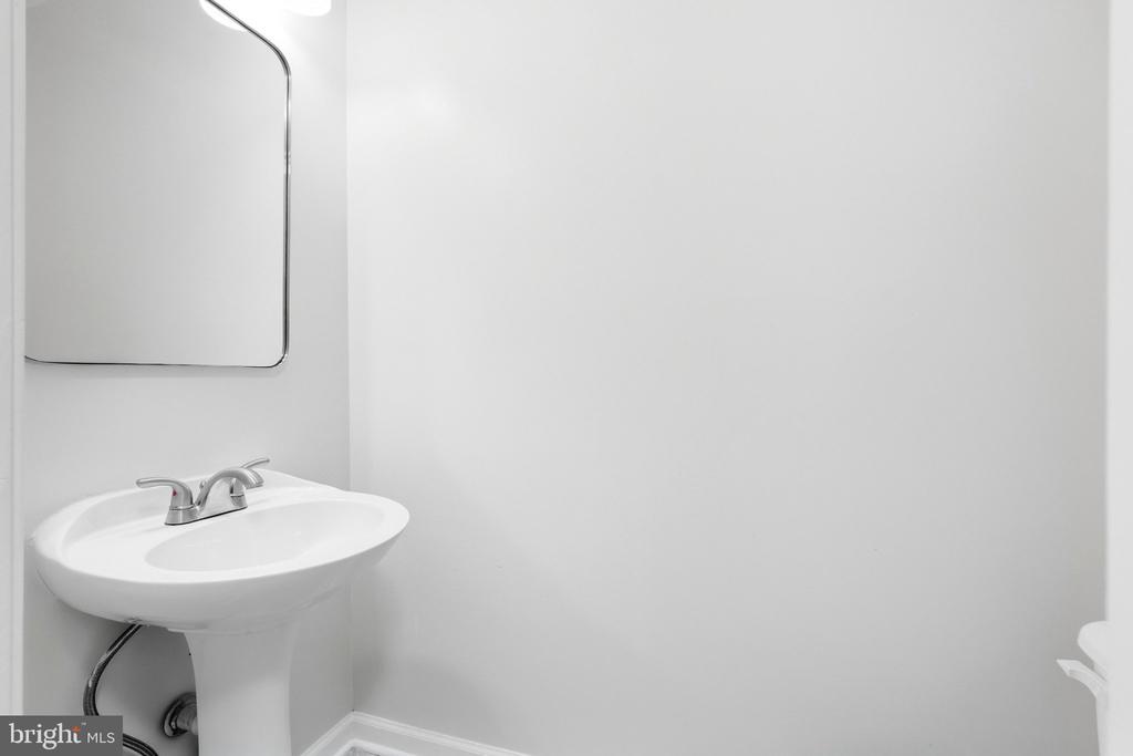 Bathroom with a white pedestal sink, chrome faucet, and wall mirror.