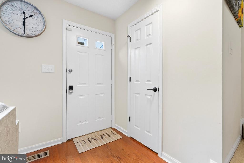 Entry foyer with a white front door, hardwood floors, and a large wall clock.