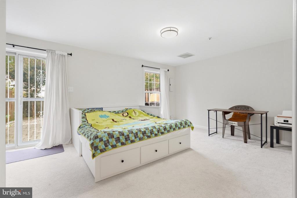 Bedroom with a white storage bed, colorful bedding, and a sliding glass door to the deck.