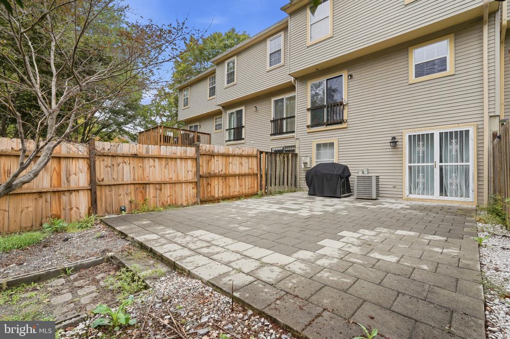 Townhouse patio with gray pavers, wooden privacy fence, and covered grill.