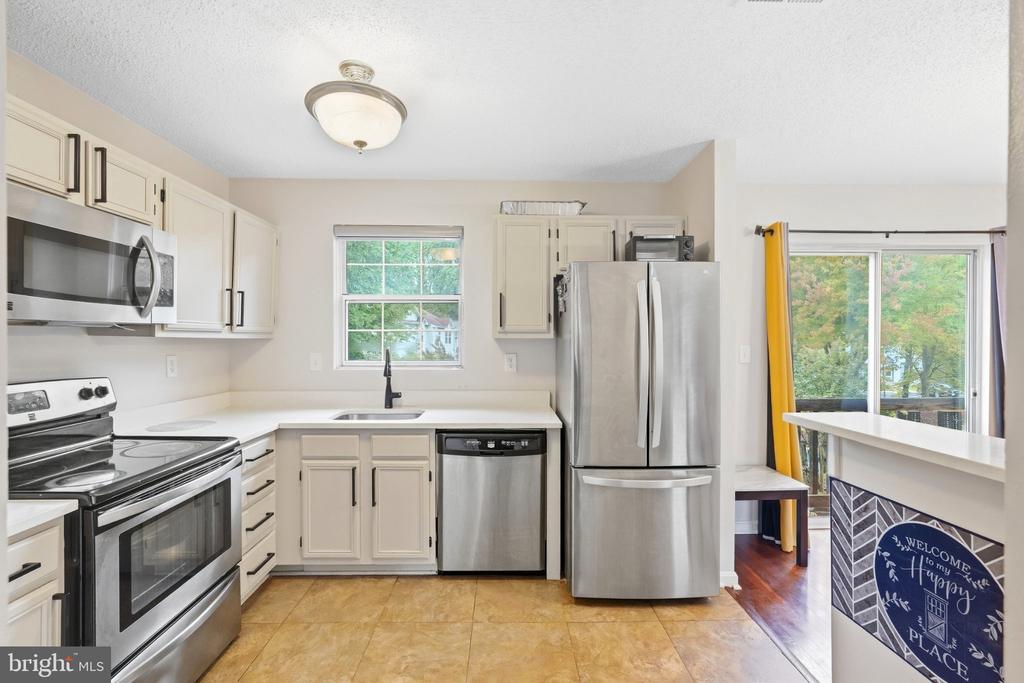 Kitchen with cream cabinets, stainless steel appliances, and a window above the sink.