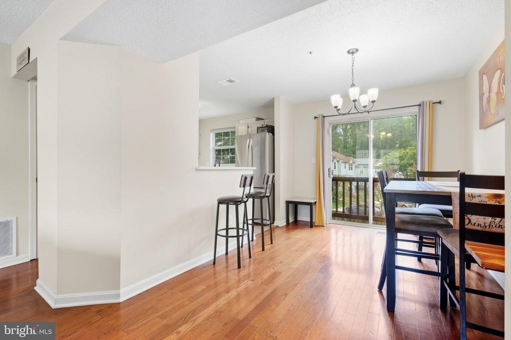 Dining area with hardwood floors, chandelier, and sliding glass doors opening to a deck.