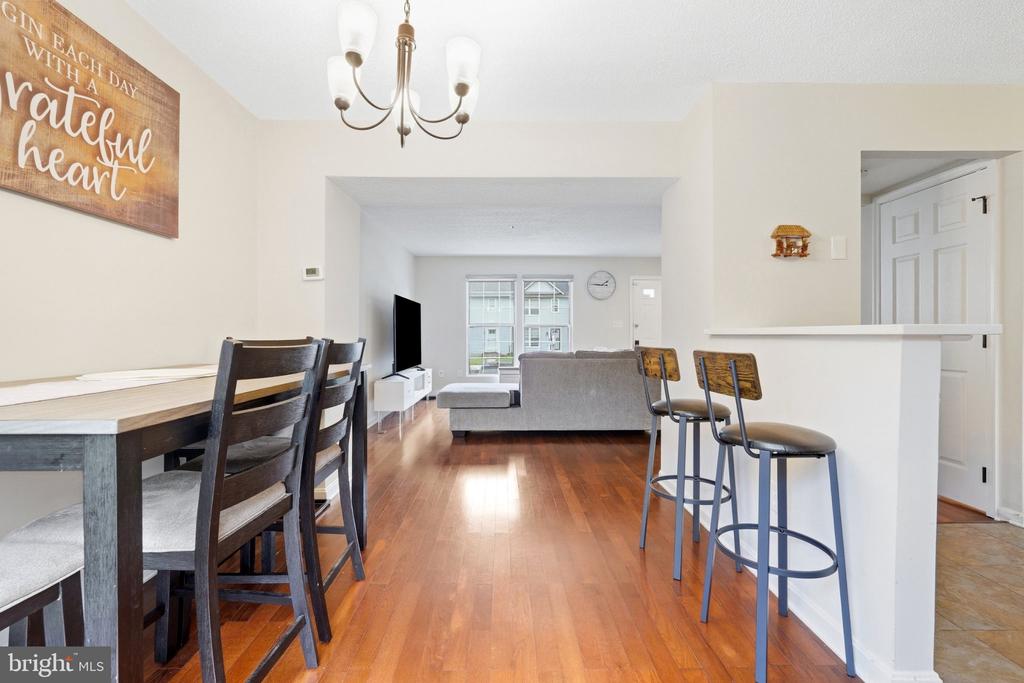 Open dining and living area with hardwood floors, a dining table, and a breakfast bar.