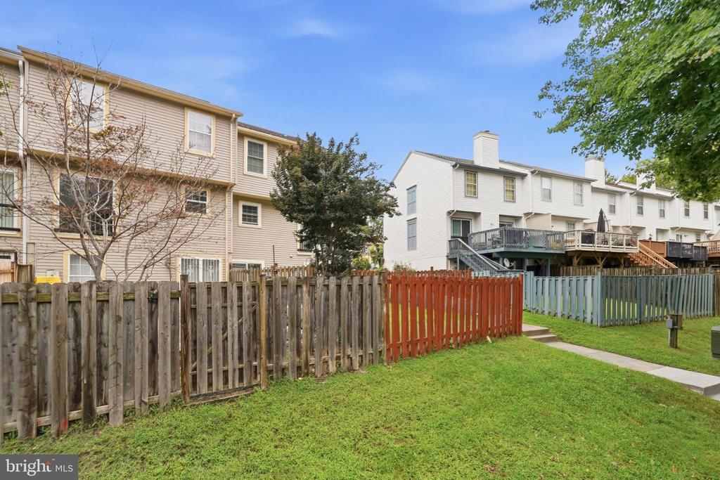 Attached townhouses with raised decks behind colorful fences and grassy yards.