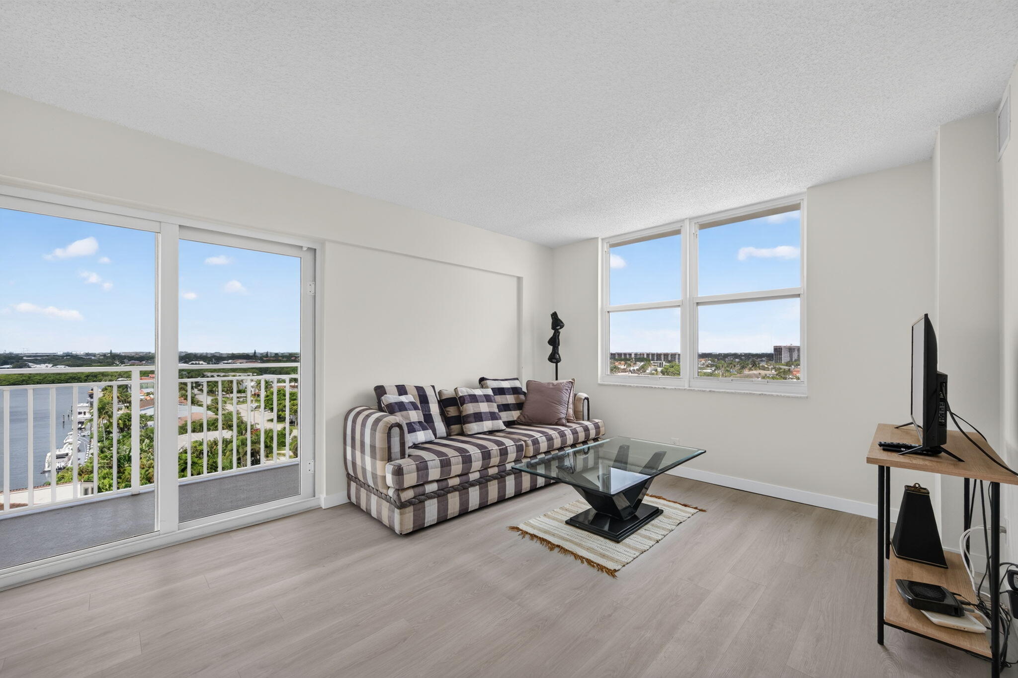 Condo living room with a plaid sofa and balcony overlooking a waterway.