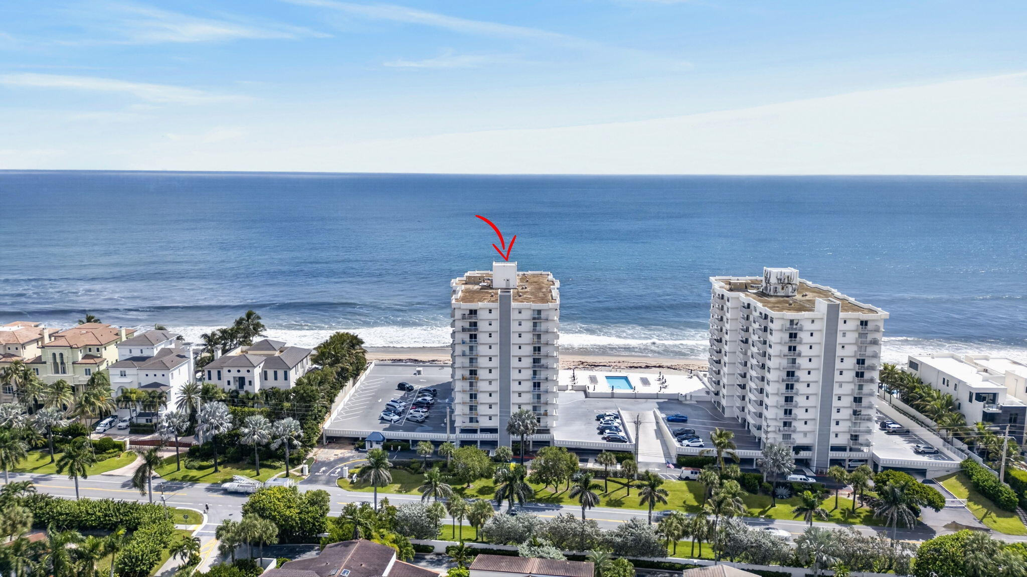 Oceanfront condominium marked by a red arrow, with beach and pool visible.
