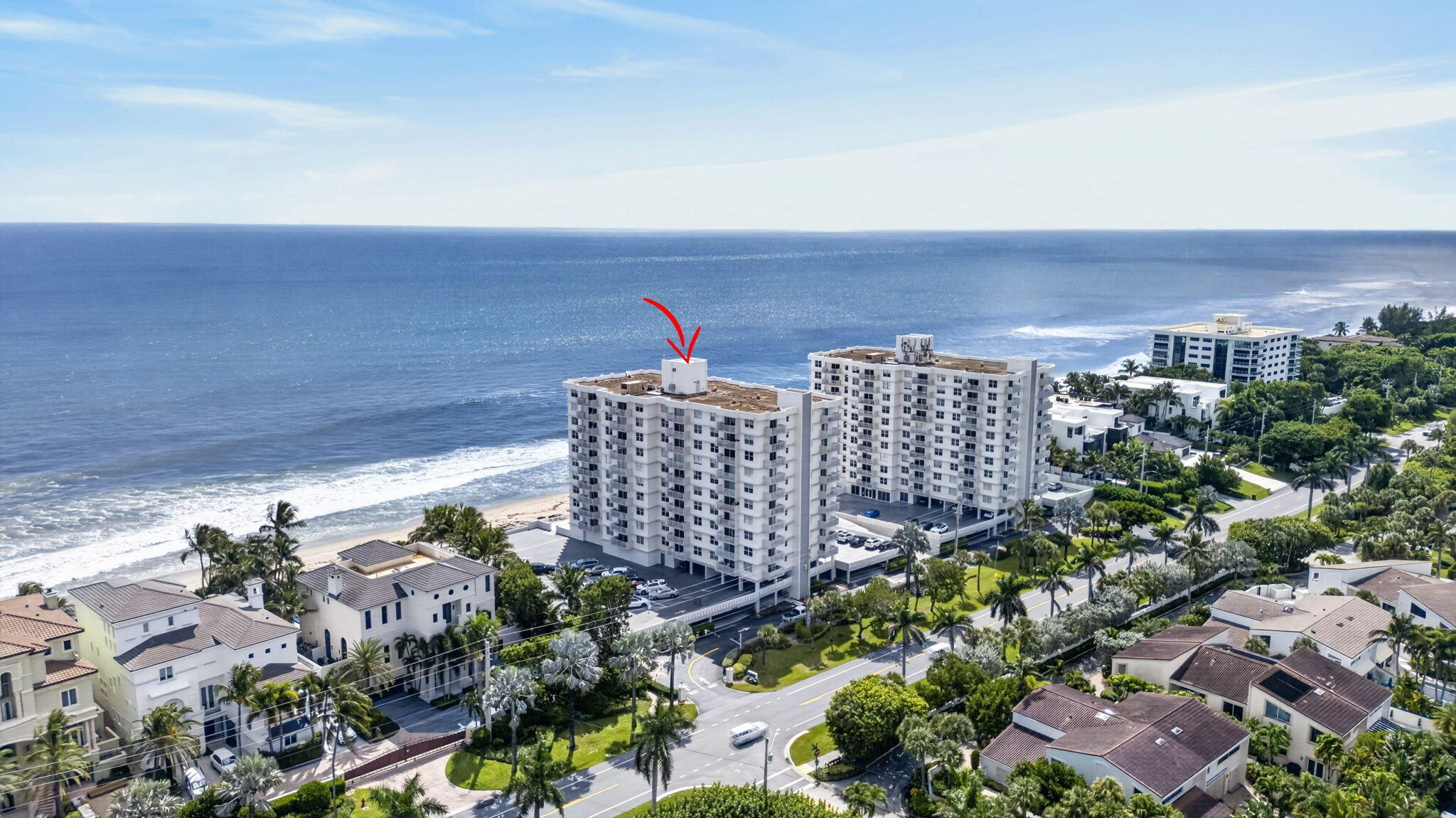Oceanfront condominium tower marked by a red arrow, with the beach and Atlantic Ocean behind it.