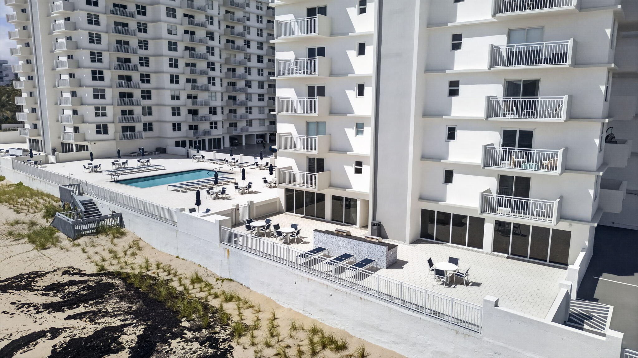 Beachfront condominium with a swimming pool and furnished sun deck beside the sand.