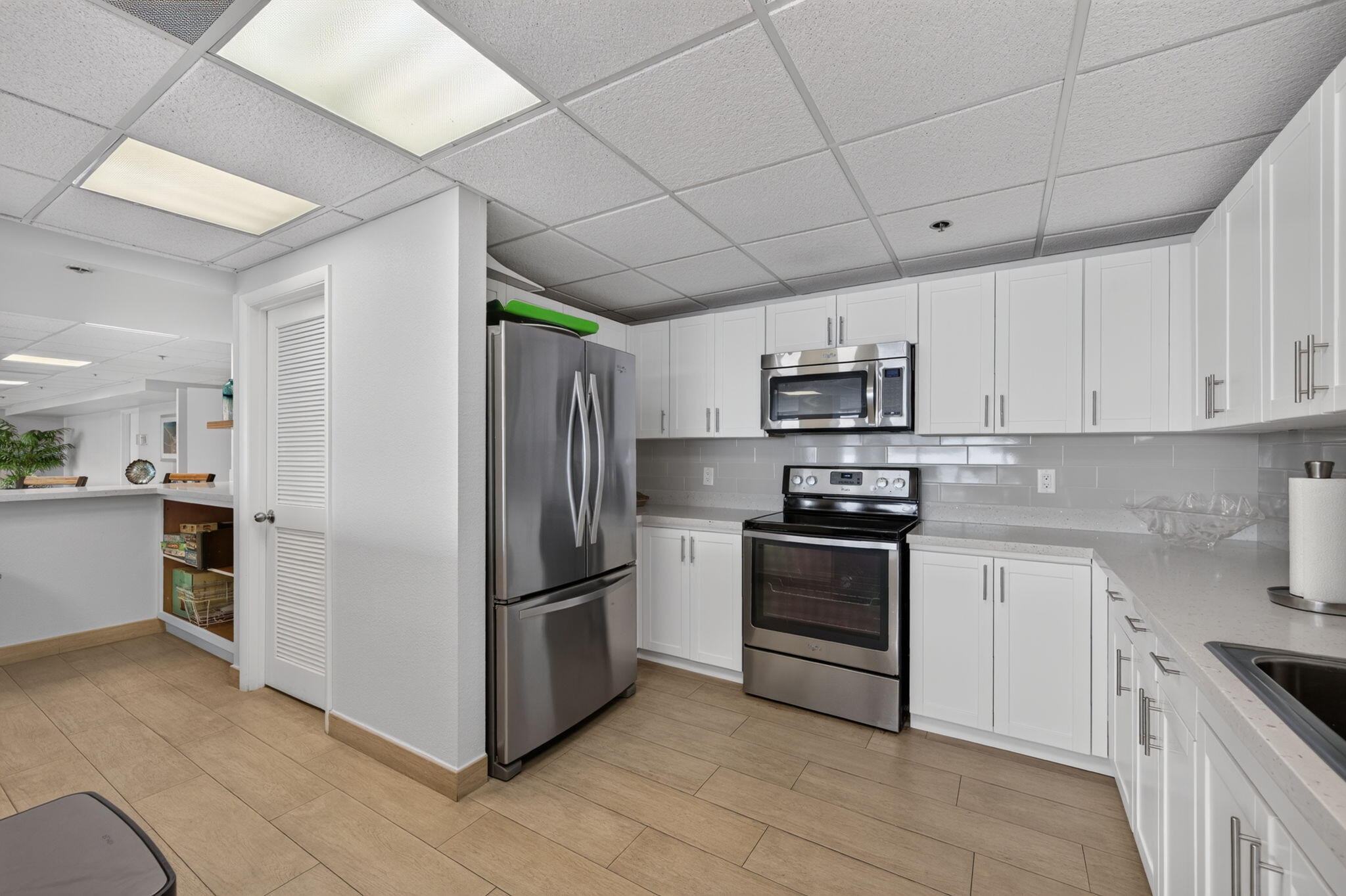 Renovated kitchen with white cabinets, stainless steel appliances, and a pass-through counter.