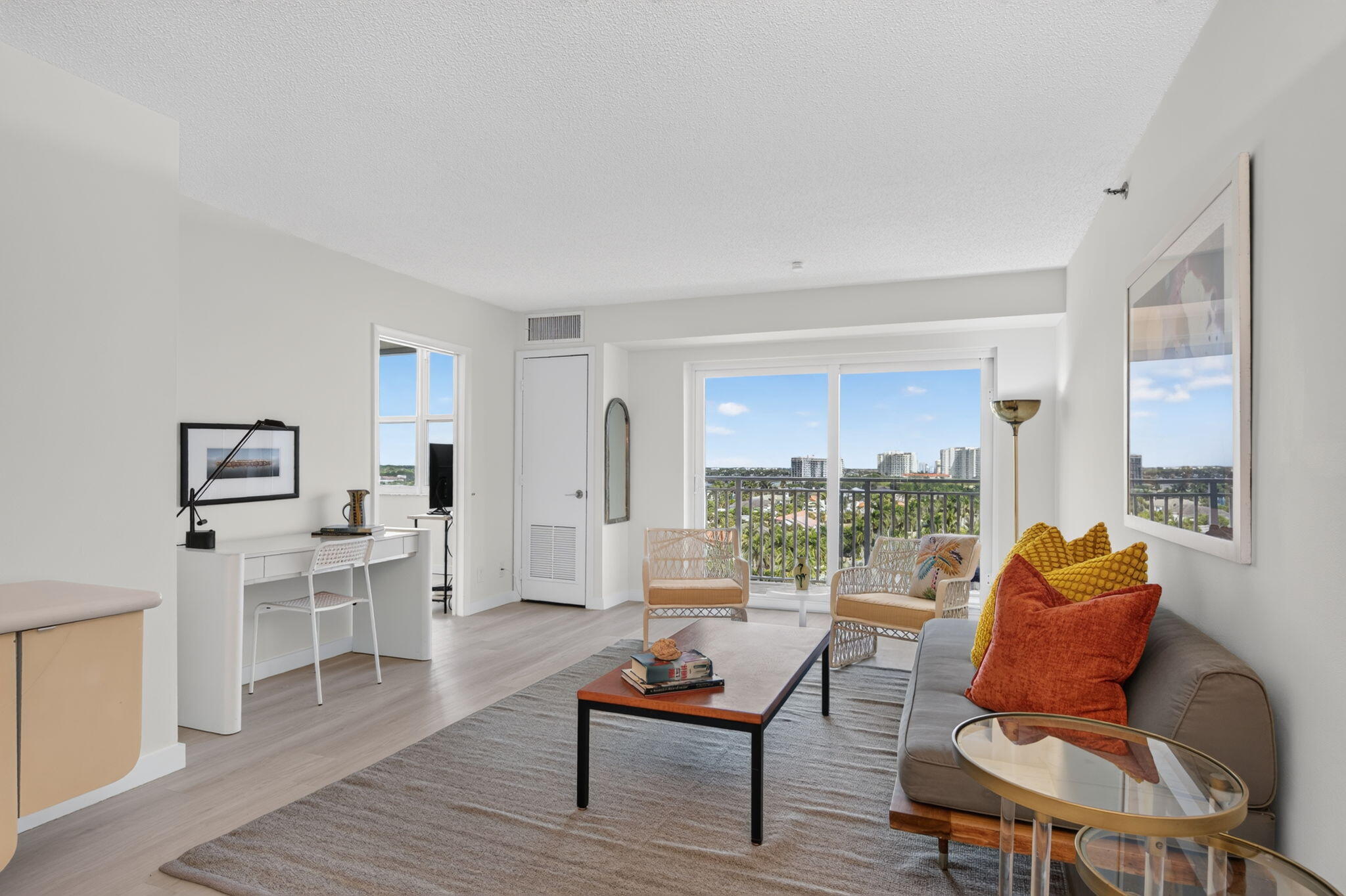 Condo living room with colorful cushions and balcony views through sliding glass doors