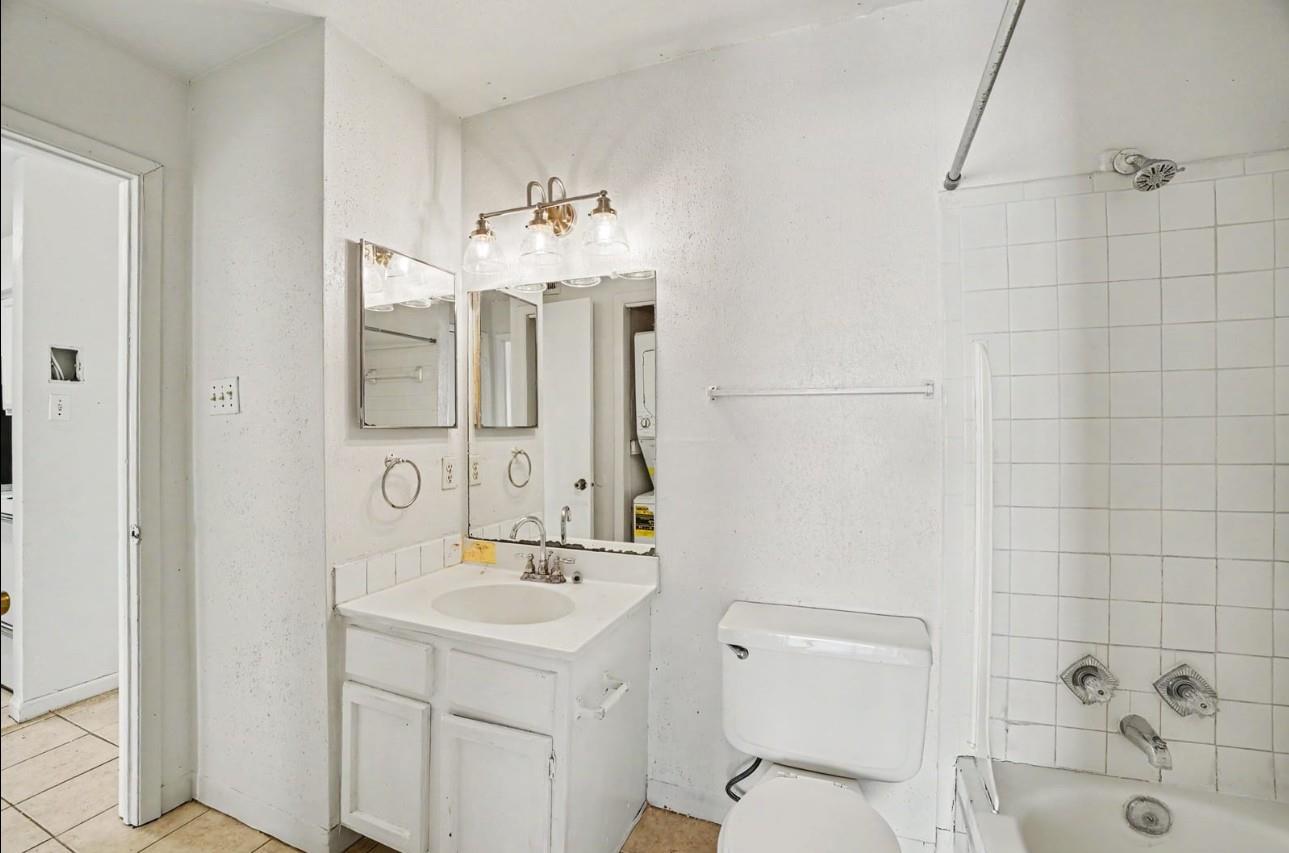Bathroom with a white vanity, toilet, and tiled bathtub and shower.