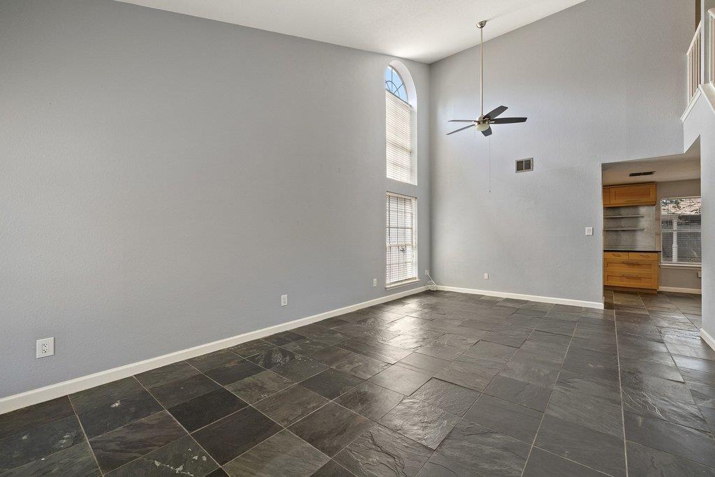Unfurnished living room with vaulted ceilings, dark tile floors, and tall arched windows.