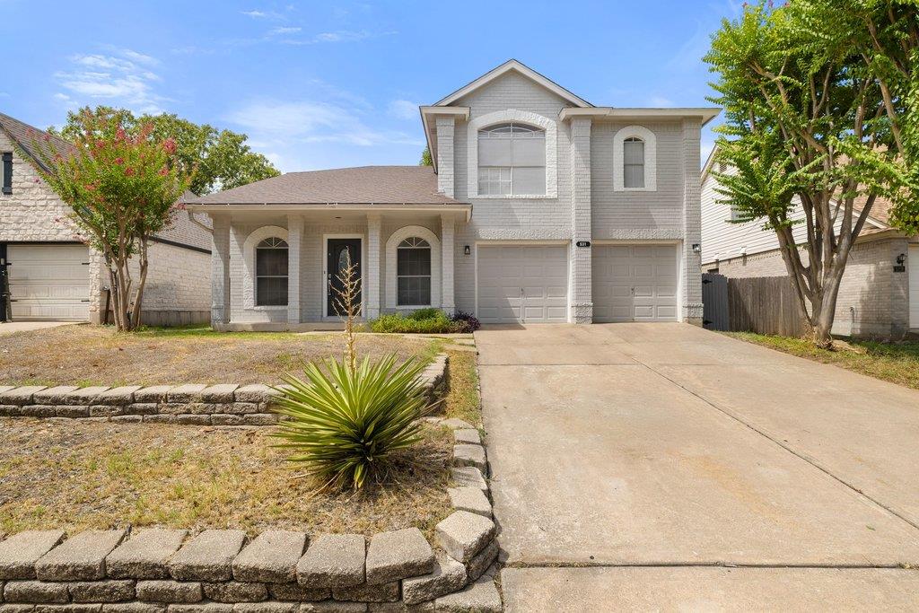 Two-story gray house with a covered porch, arched windows, and a wide driveway.